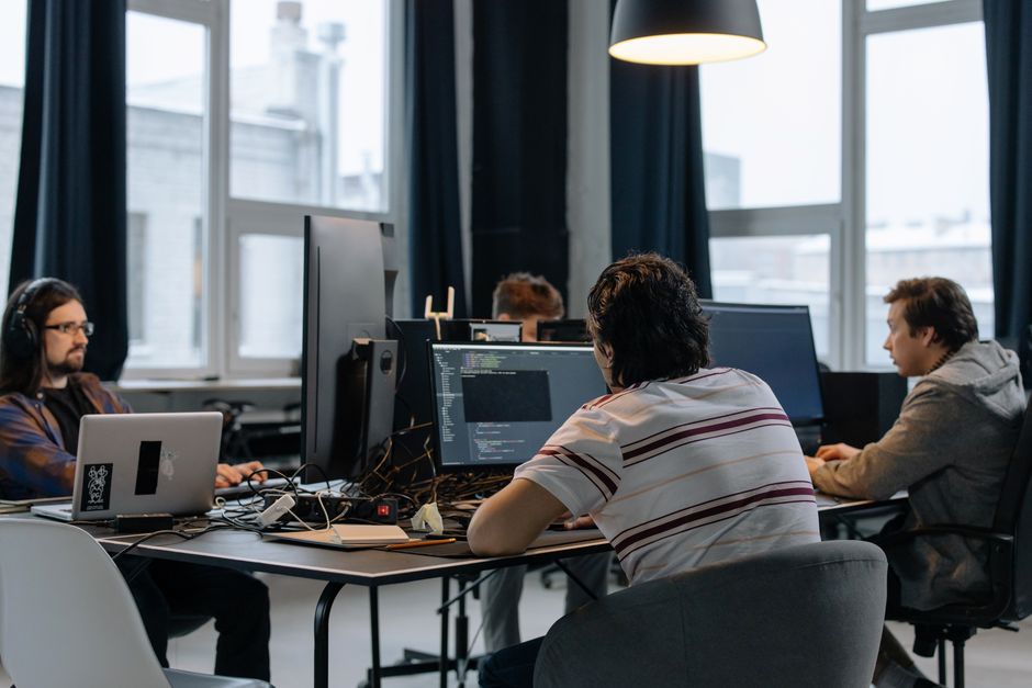 Timovi developera radi zajedno na računalima u modernom tech uredu
