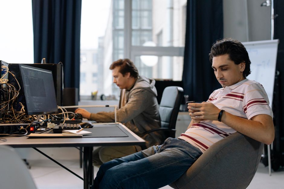 Dva stručnjaka rade u modernom uredu, jedan na računalu drugi na mobitelu
